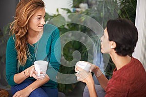 Is that so. Shot of two female professionals having a discussion over coffee in an informal office setting.