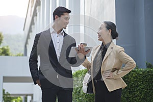 Shot of two successful business people talking to each other while walking outdoors at the city streets