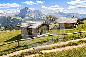 Shot of two wooden cabins on a meadow with the mountains in the background