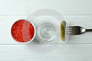 Shot of vodka, caviar and pickle on white wooden background