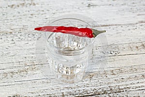 Shot of vodka with pepper on an old wooden table