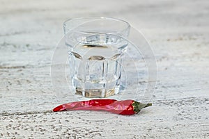 Shot of vodka with pepper on an old wooden table