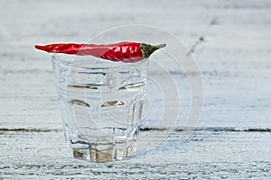 Shot of vodka with pepper on an old wooden table