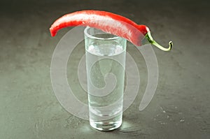 Shot of vodka and red pepper/shot of vodka and red pepper on a dark stone background