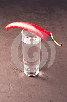 Shot of vodka and red pepper/shot of vodka and red pepper on a dark stone background. Close up