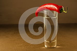 Shot of vodka and red pepper/shot of vodka and red pepper on a dark stone background. Selective focus and copyspace