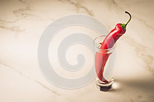 shot of vodka and red pepper/shot of vodka and red pepper on a white marble background. Selective focus and copyspace