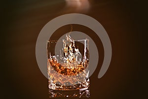 shot of whiskey with splash on black background, brandy in a glass