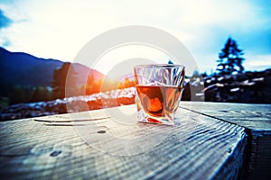 shot of whiskey at sunset dramatic sky on mountain landscape background