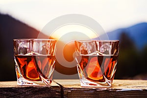 shot of whiskey at sunset dramatic sky on mountain landscape background