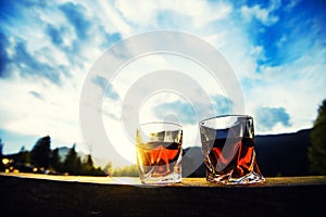 shot of whiskey at sunset dramatic sky on mountain landscape background