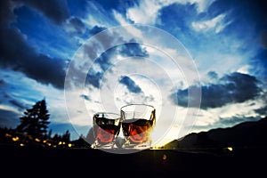 shot of whiskey at sunset dramatic sky on mountain landscape background