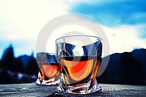 shot of whiskey at sunset dramatic sky on mountain landscape background