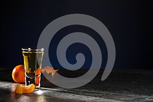 Shot of whiskey and tangerines, peeled and unpeeled on a beautiful dark blue background. Copy space.