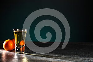 Shot of whiskey and two tangerines on a beautiful dark green background. Copy space.