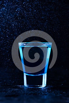 Shot with White Rum and Liquor Blue Curacao. Alcoholic Layer Cocktail on Dark Background