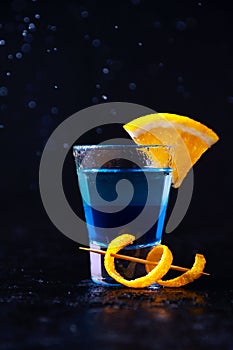 Shot with White Rum, Liquor Blue Curacao and Orange Slice. Alcoholic Layer Cocktail on Dark Background