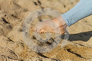 Shot of a woman's barefoot legplaying with sand, Barceloneta beach, Barcelona, Spain