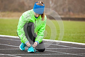Shot of a woman tying her shoelaces on running shoes.