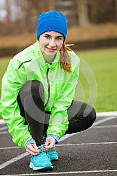 Shot of a woman tying her shoelaces on running shoes.