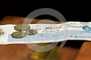 Some old british coins sit on top of a bank cheque from 1940 during world war 2