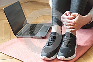 Shot of a yound woman at home, ready for follow your online class of yoga. Sneakers close up. Laptop. Home workout concept