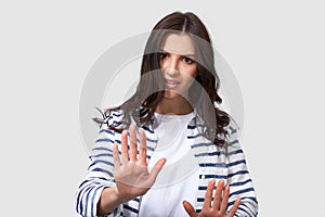 Shot of young brunette woman making stop gesture with her palms. Portrait of Caucasian female, making rejection gesture
