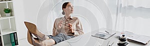 Shot of young businesswoman procrastinating at workplace with feet on table in office