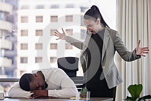 Why are you sleeping. Shot of a young female boss looking angry while a coworker sleeps in an office at work.