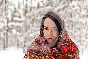 Shot of young woman in a  colorful  headscarf against the backdrop of a winter snowy forest