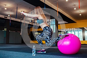 Shot of young woman exercising at the gym. Muscular female training using a ball. Woman doing sit-ups.