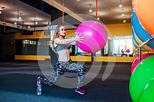 Shot of young woman exercising at the gym. Muscular female training using a ball. Woman doing sit-ups.