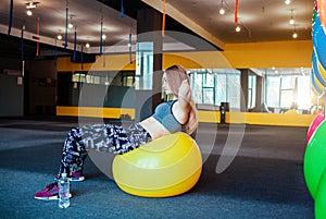 Shot of young woman exercising at the gym. Muscular female training using a ball. Woman doing sit-ups.