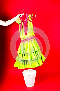 Shot of a young woman hand throwing her outwear dress in the trash isolated on red background