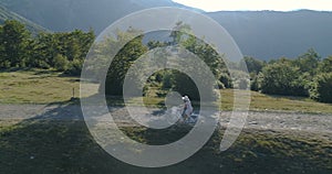 Shot of a young womanin a light dress and hat riding bicycle on rural road