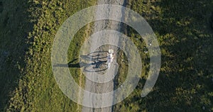 Shot of a young womanin a light dress and hat riding bicycle on rural road