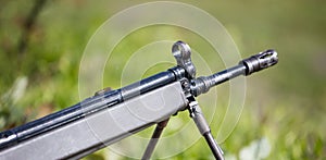 Shotgun on easel. Front side of weapon with close up view on blurred nature background.