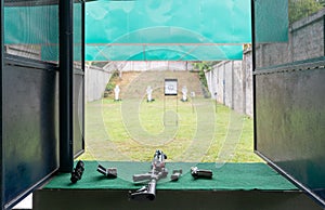Shotgun and handgun with bullets on a Green table in Shooting Range. Practicing Fire Pistol training Shooting.
