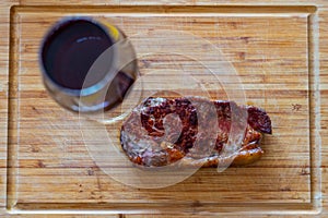 Shots of a sliced fresh rump steak with fat on the steak on a wooden board and a glass of wine