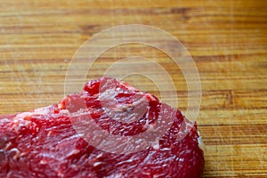 Shots of a sliced raw  fresh rump steak with fat on the steak on a wooden board