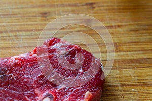 Shots of a sliced raw  fresh rump steak with fat on the steak on a wooden board