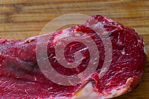 Shots of a sliced raw  fresh rump steak with fat on the steak on a wooden board