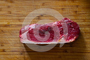 Shots of a sliced raw  fresh rump steak with fat on the steak on a wooden board