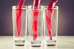 shots of vodka and red pepper/ Drink set with three shots of vodka and red pepper on a white marble background