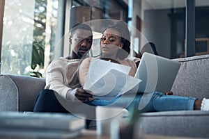 Should we reinvest this money. a young couple sitting on the sofa together and using a laptop while going through their