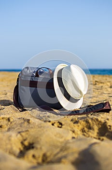 Shoulder bag and white hat on the sand of the beach