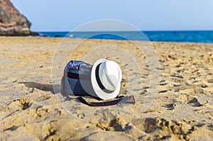 Shoulder bag and white hat on the sand of the beach