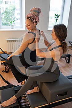 Pilates instructor adjusts posture, instructor meticulously corrects shoulder posture during session