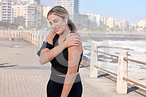 Shoulder pain, fitness woman and music of a person running by the sea with a arm injury. Workout, sports and training