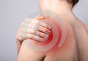Shoulder pain and trigger points. Naked woman holding painful shoulder with red spot closeup. Joint injuries. Health
